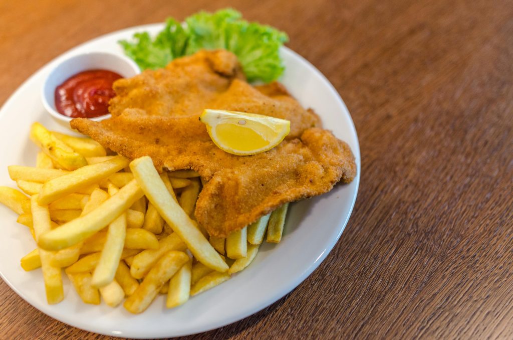 Delicious schnitzel served with crispy french fries, ketchup, and fresh lettuce on a plate.